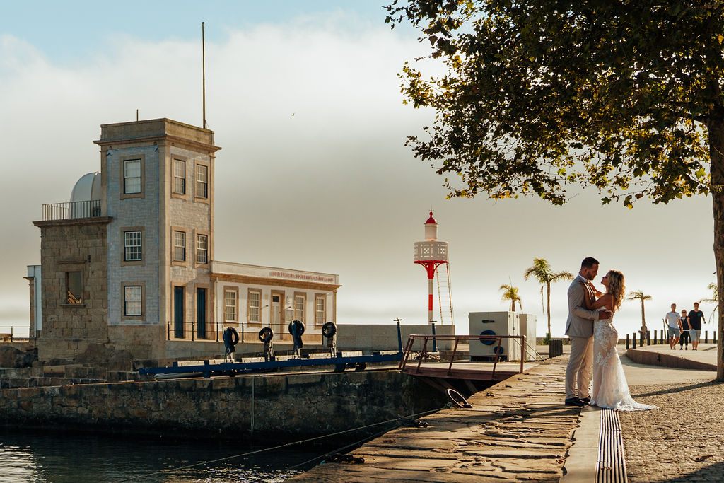 Casal junto a um farol à beira-mar